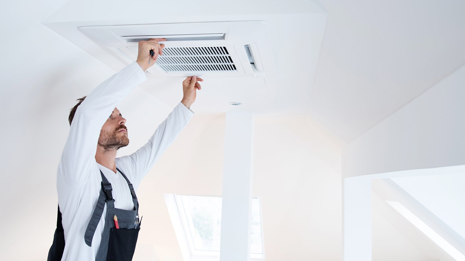 worker checking vent in house