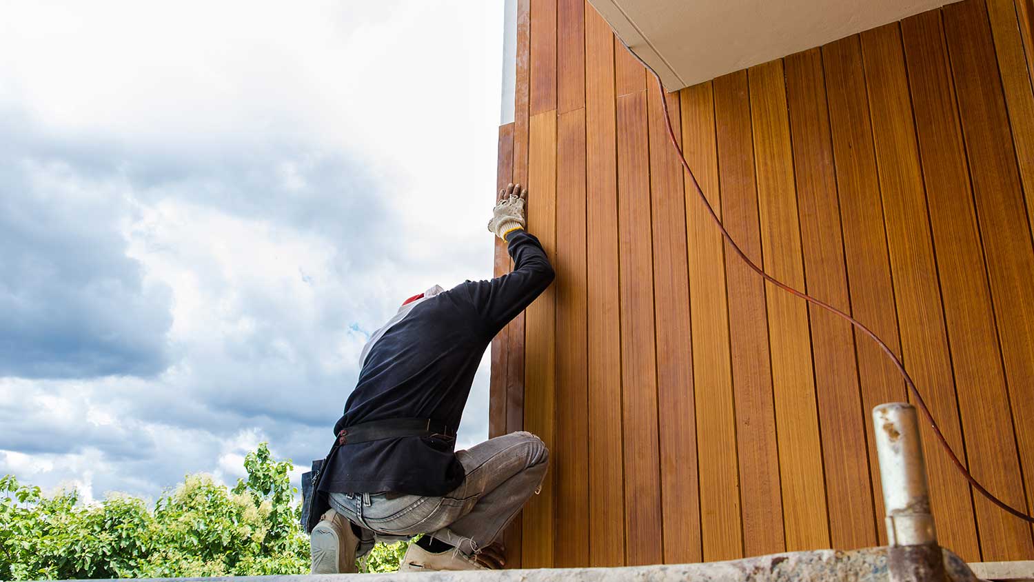 Worker installing engineered wood siding