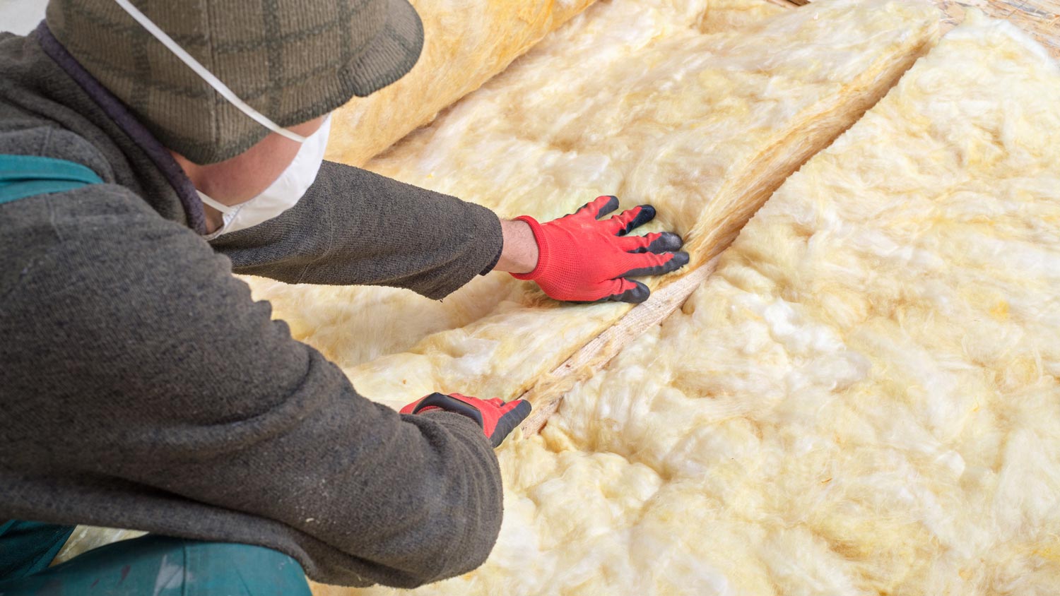 A worker laying mineral wool for floor insulation