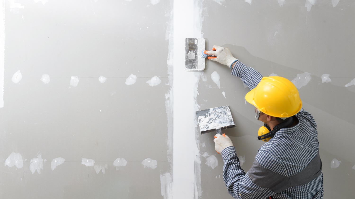 A worker plastering the wall indoors