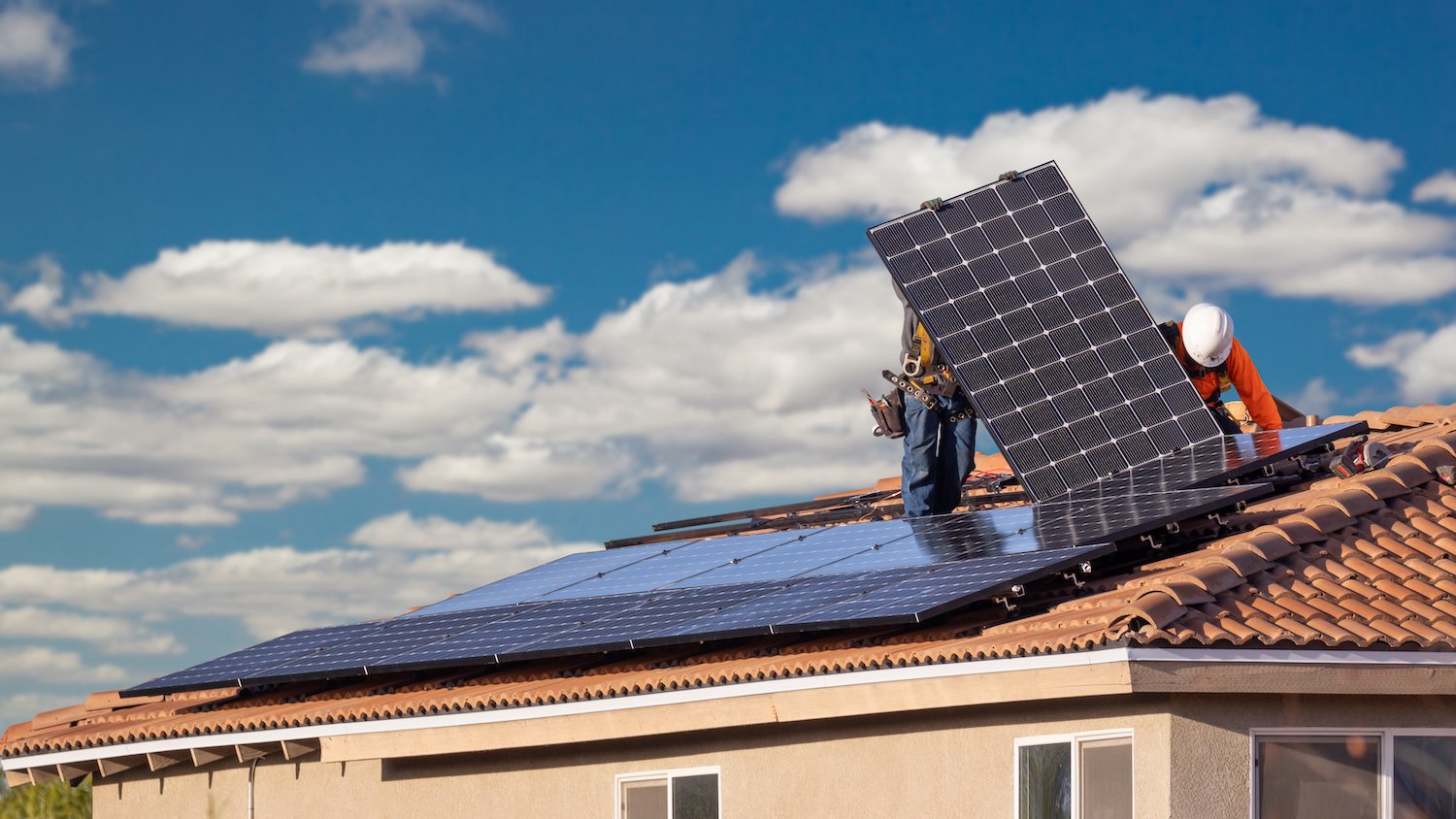 Workers installing solar panels on a roof