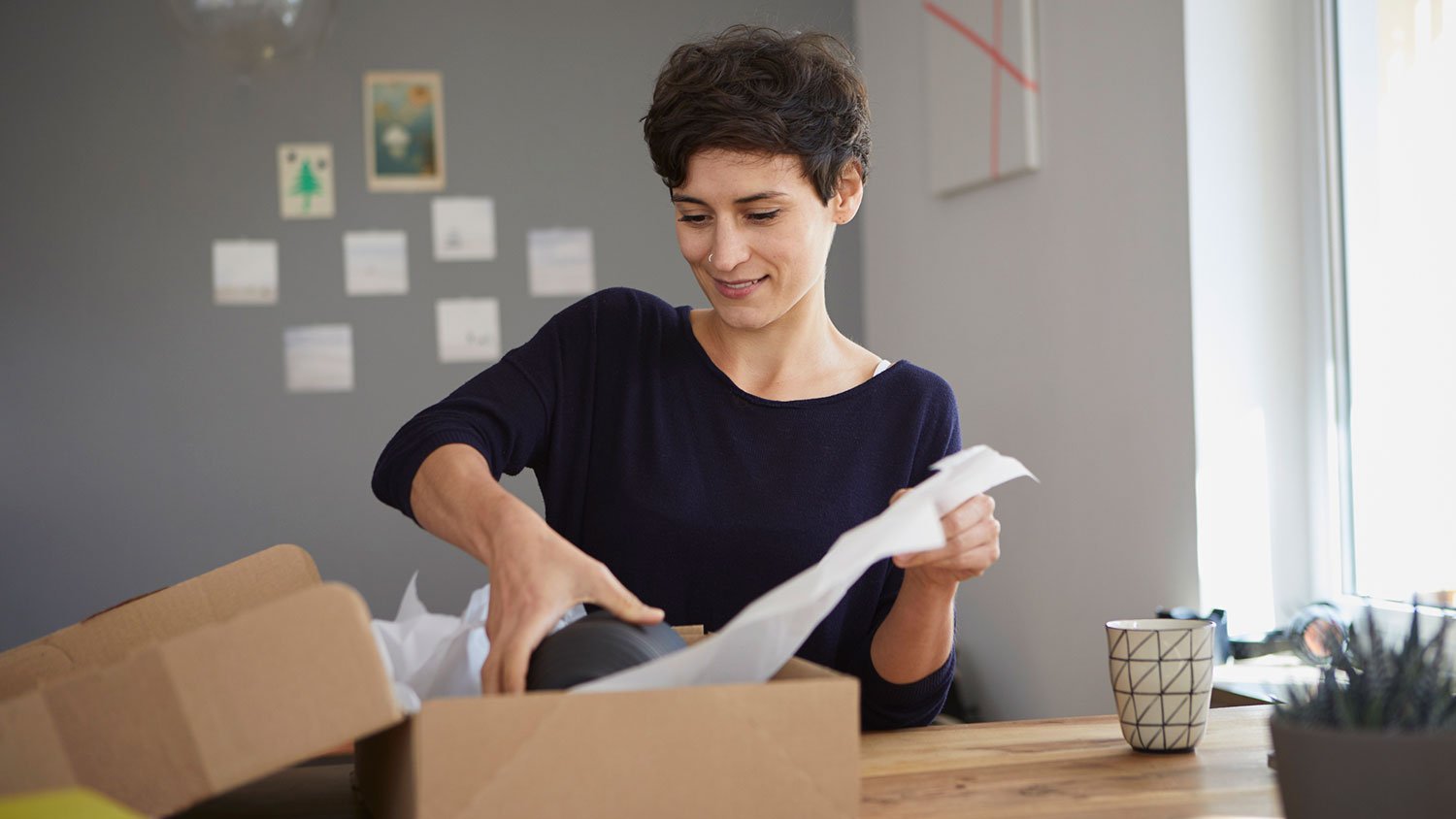 Woman packing ceramic vase in a box