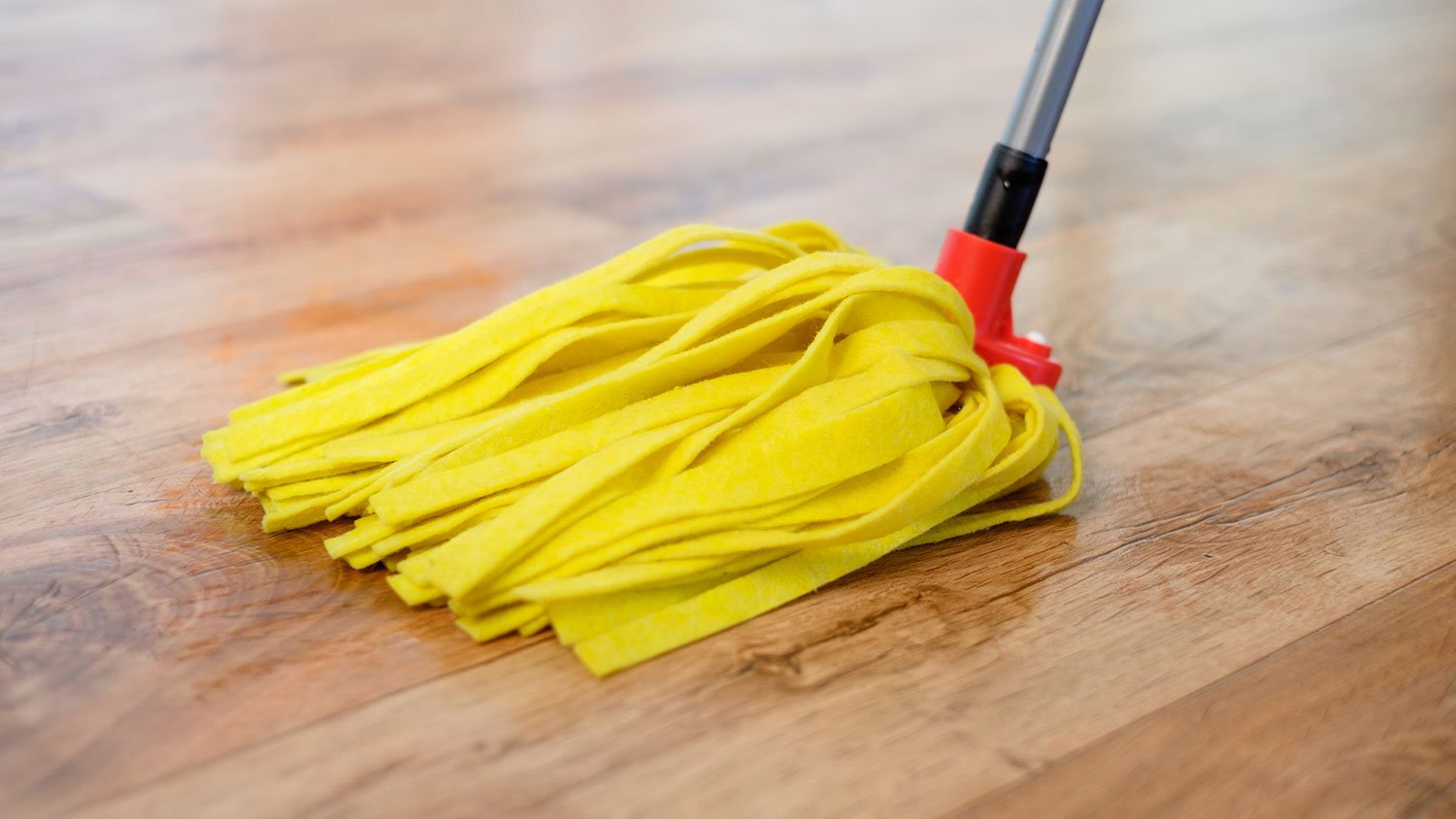 Closeup of a yellow mop on a laminate floor